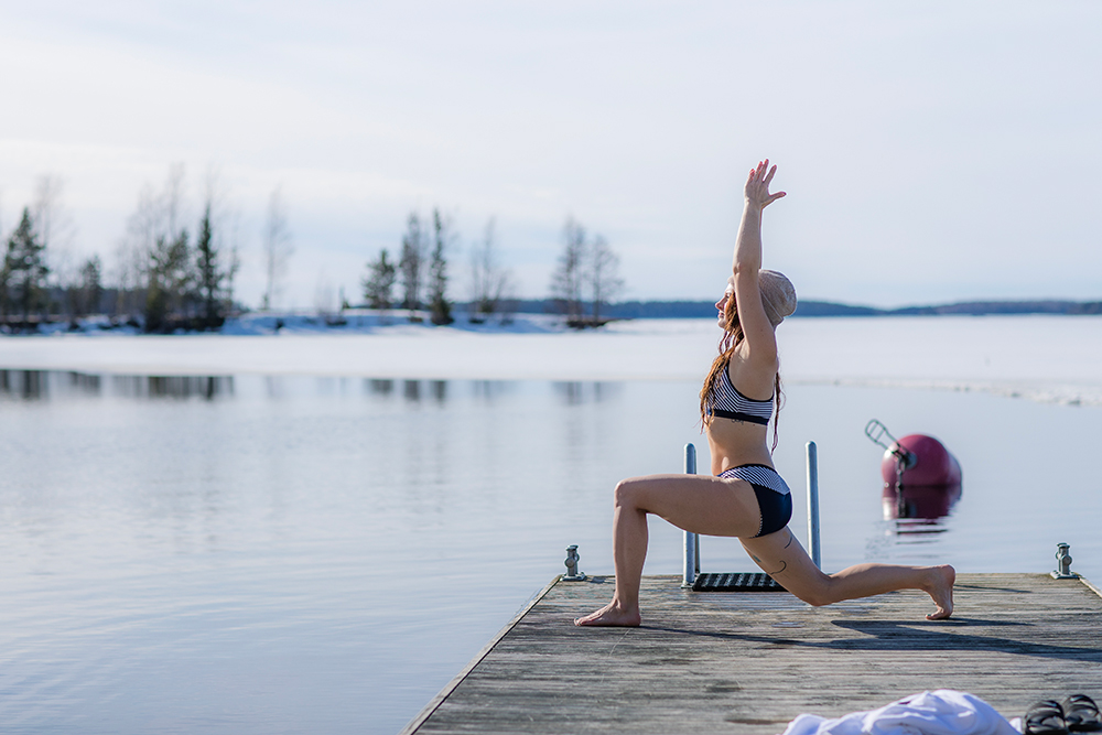 Women does yoga after a cold plunge in the frozen lakes of Finland, a key aspect of sisu